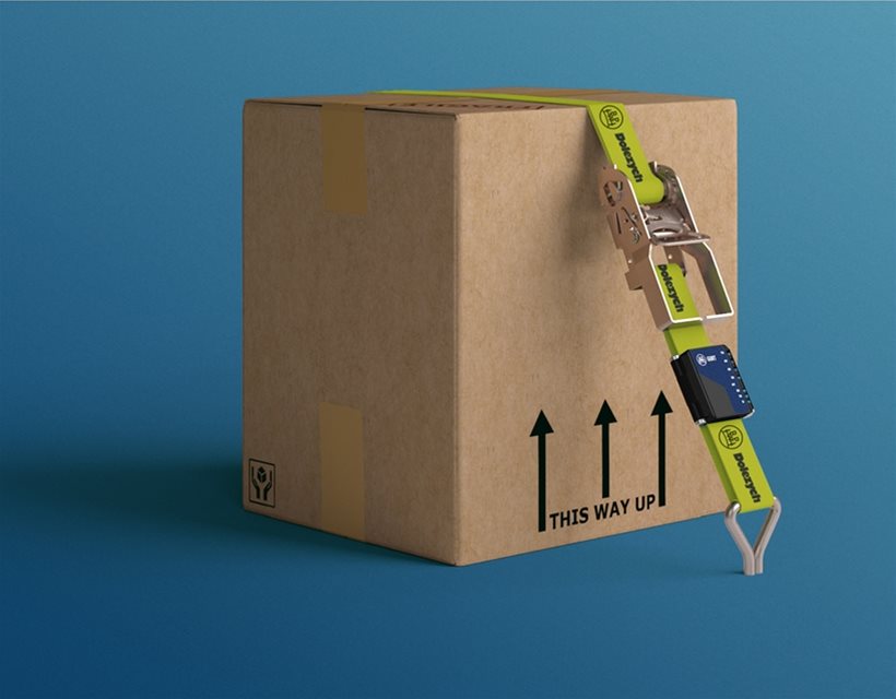 A carboard box being held down by cargo securing straps