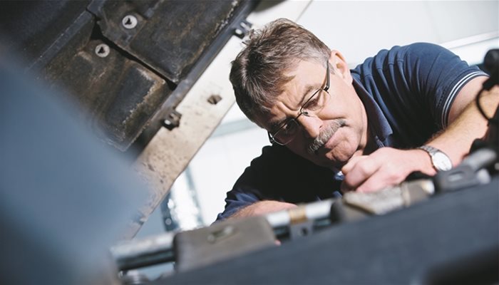 A person in glasses working on vehicle components 