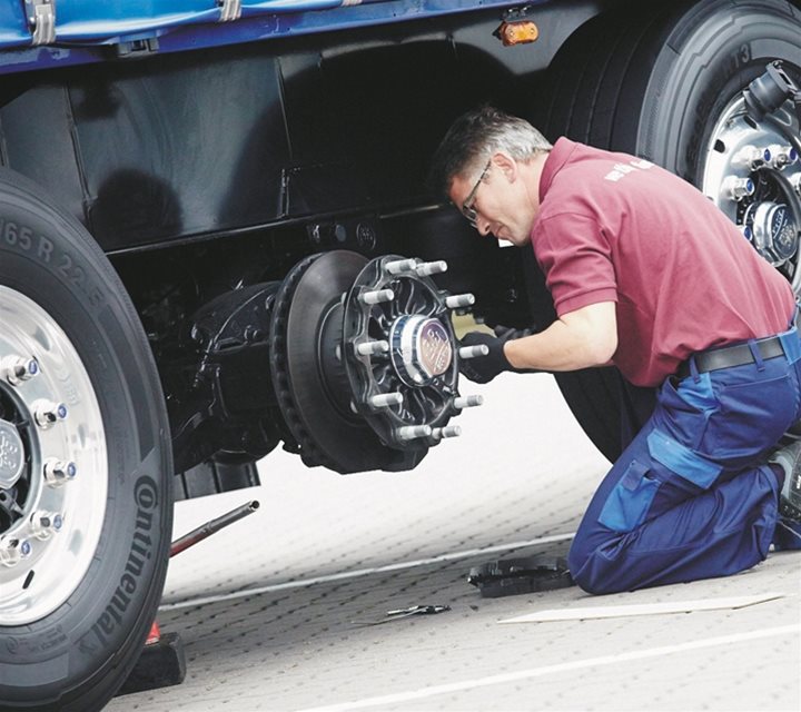 A person kneeling down and installing eco drum brakes 