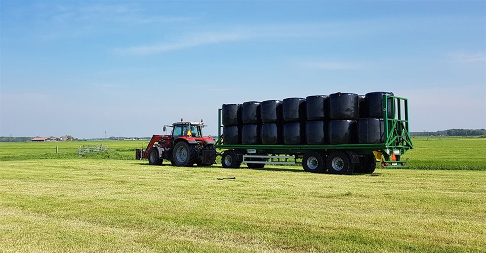 A tractor pulling along a trailer filled with black containers
